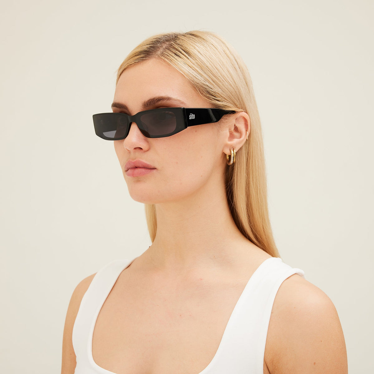 Woman wearing black sunglasses with a neutral background