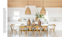 Modern kitchen with wooden dining table and chairs, white cabinets, and pendant lights.