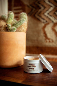 Jar of horchata latte on a wooden surface with a plant in the background