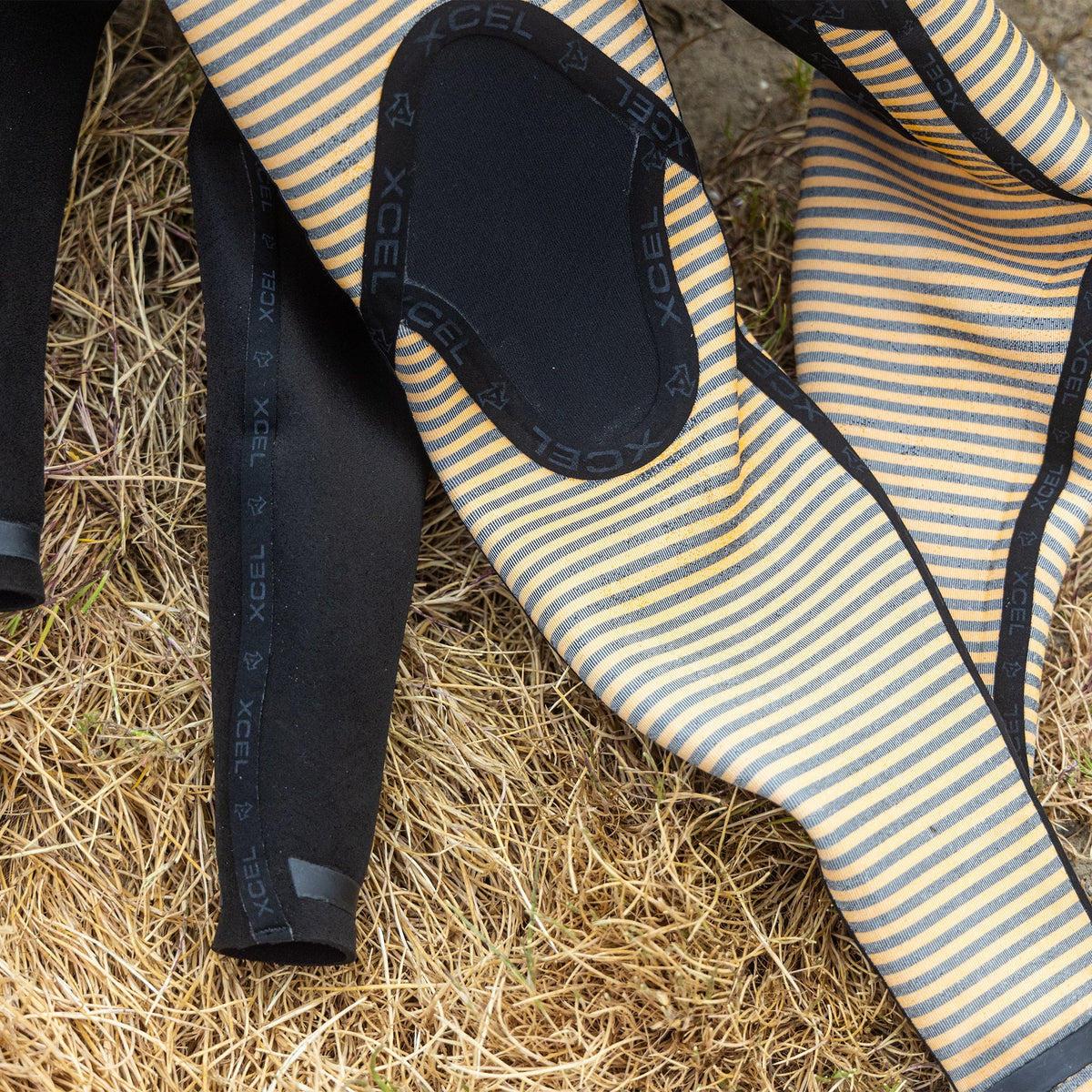 Close-up of striped wetsuit on grass with XCEL branding