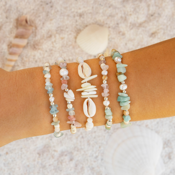 Beach-themed bracelet set on a wrist with a sand background