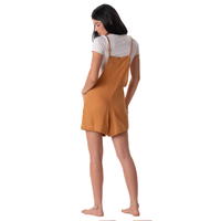 Woman wearing a mustard yellow pinafore dress over a white shirt on a white background