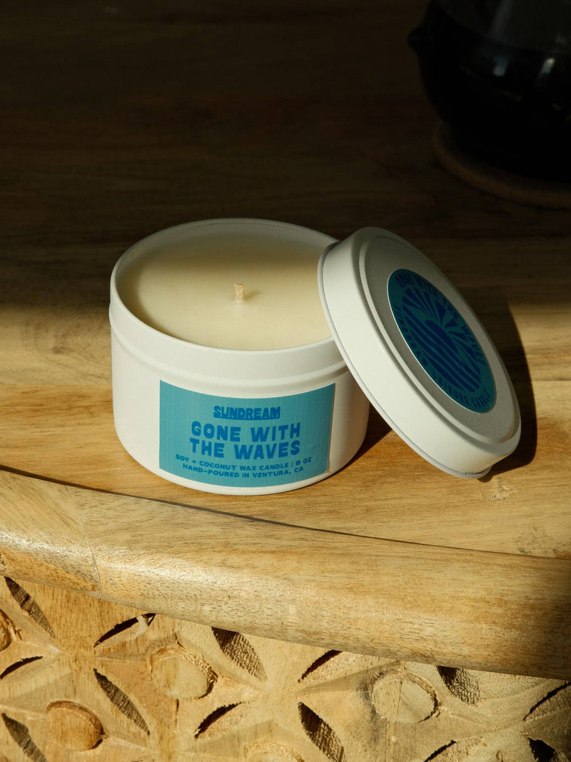 Candle in a white container with a blue label on a wooden surface