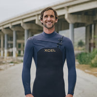 Man wearing a blue XCEL wetsuit standing outdoors with a blurred background