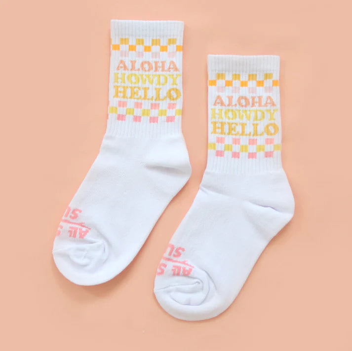 White socks with 'Aloha Howdy Hello' text on a peach background