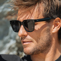 Man wearing black sunglasses with a blurred natural background