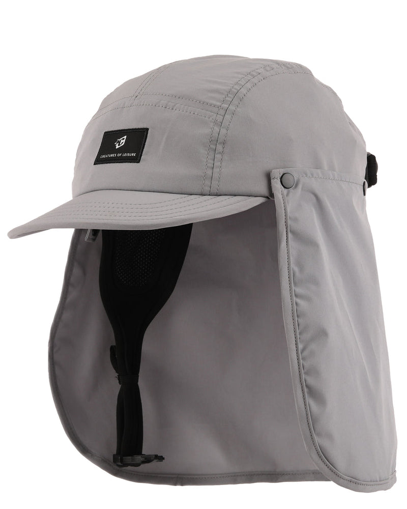 A light gray outdoor cap with an attached neck flap and chin strap, shown on a plain white background. A small black brand patch on the front 