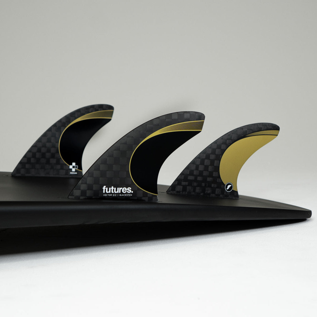 GOLD AND BLACK SURFBOARD FINS ON A BLACK SURFBOARD 