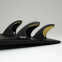 GOLD AND BLACK SURFBOARD FINS ON A BLACK SURFBOARD 