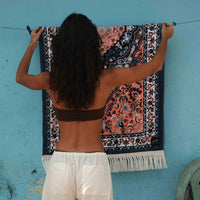 Person hanging a patterned towel on a line against a blue wall