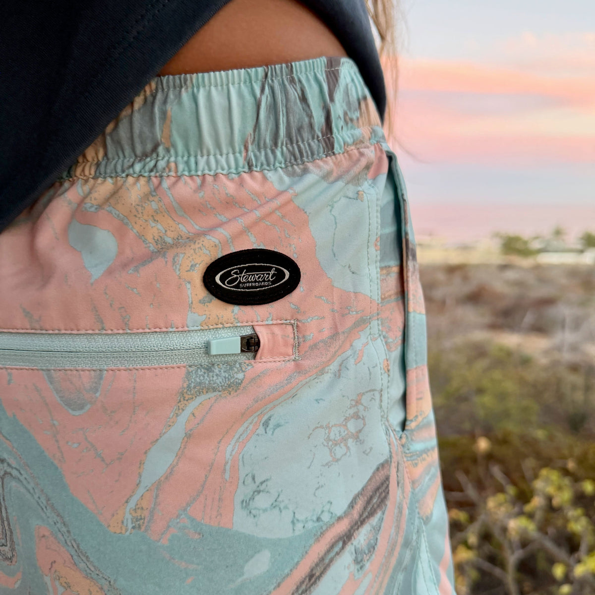Person wearing a patterned shorts with a sunset in the background