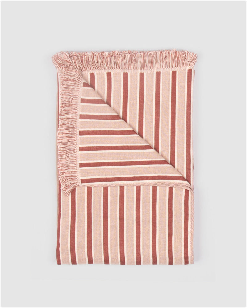 Striped blanket with frayed edges on a light gray background