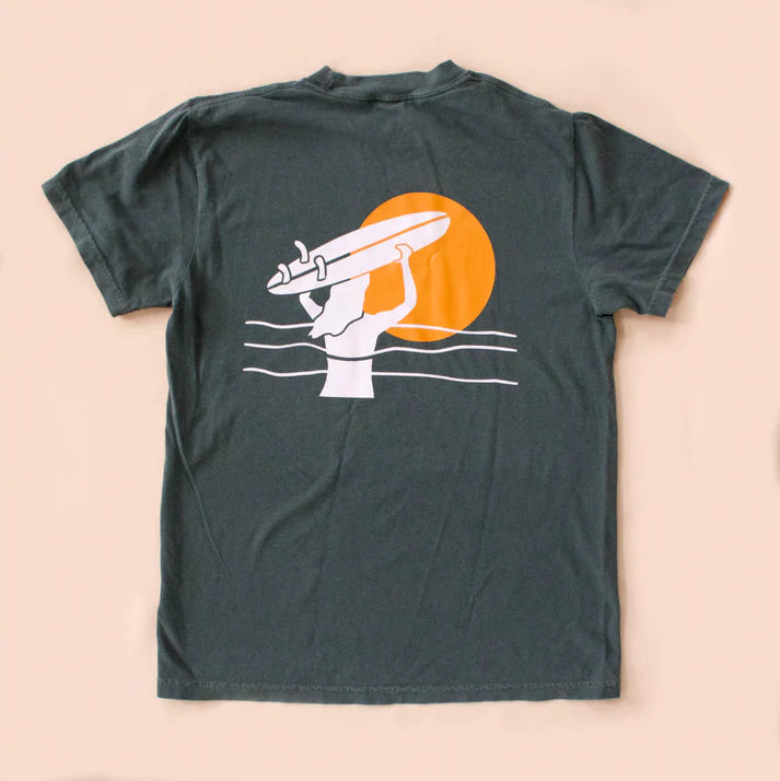 Dark green t-shirt with a graphic of a hand holding a surfboard against an orange sun on a beige background