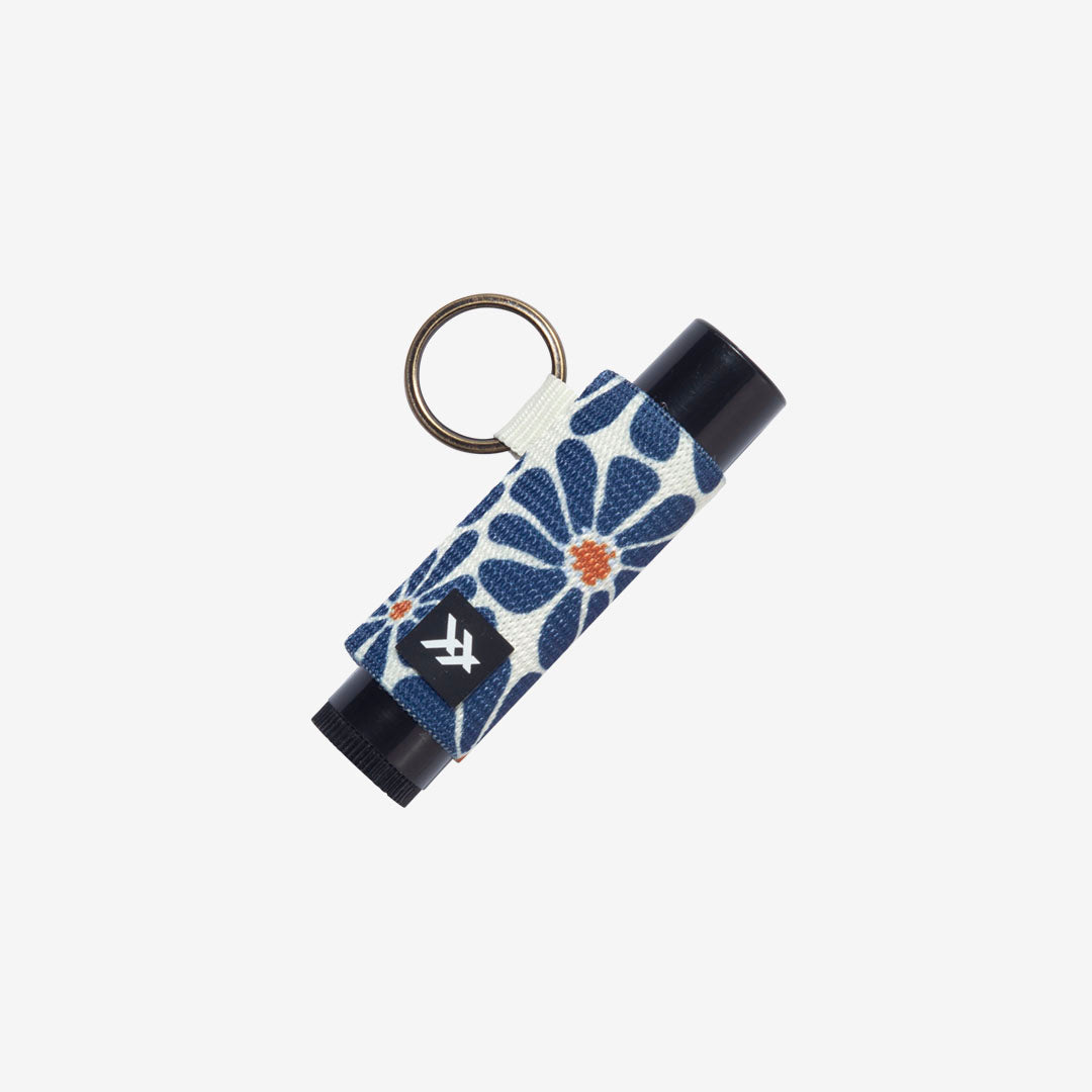 Keychain with floral design and black container on a white background