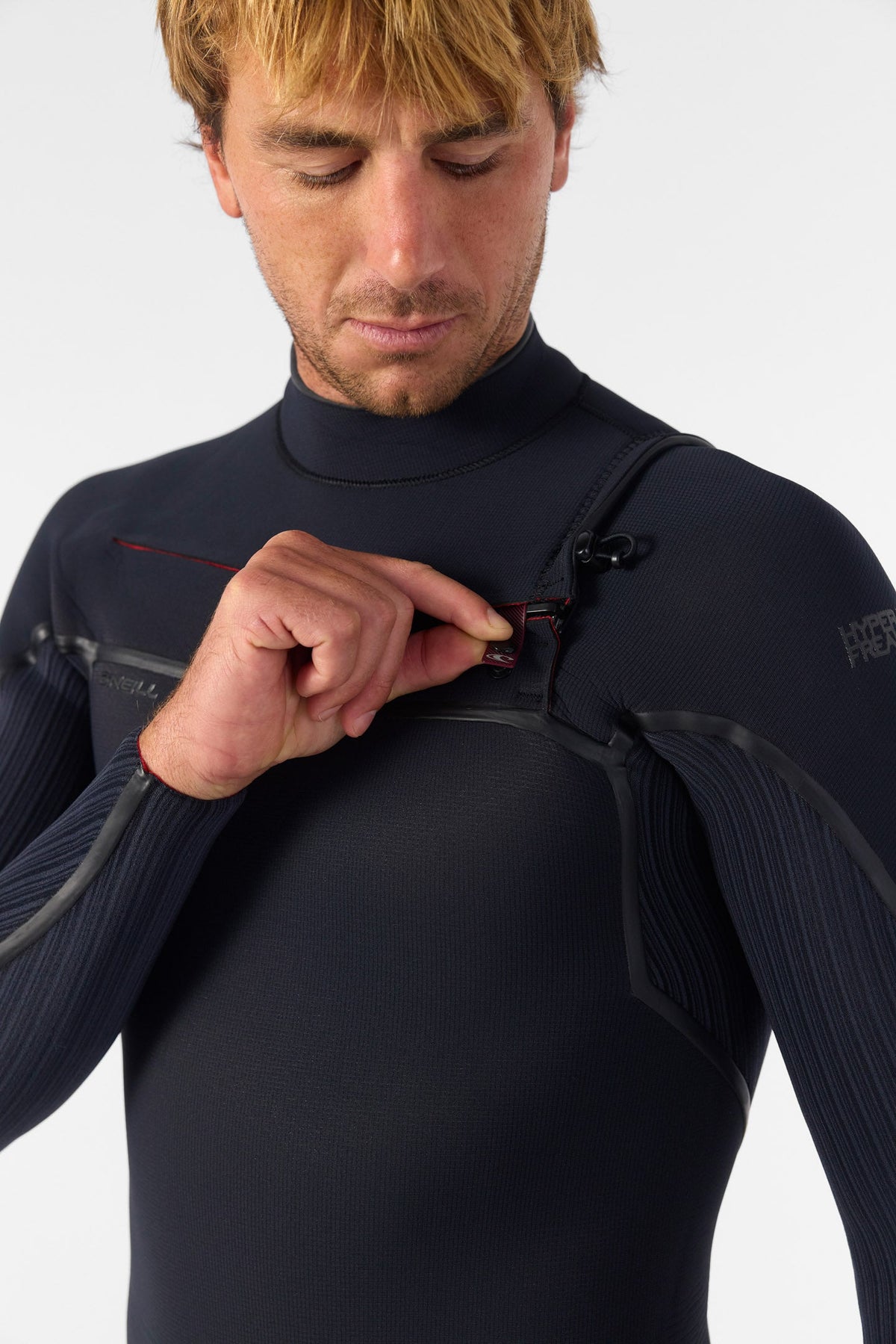 Man adjusting a black wetsuit on a white background