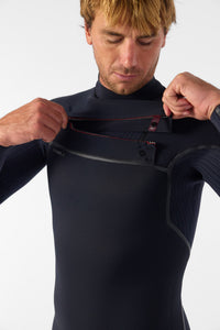 Person wearing a black wetsuit adjusting the chest zipper against a white background