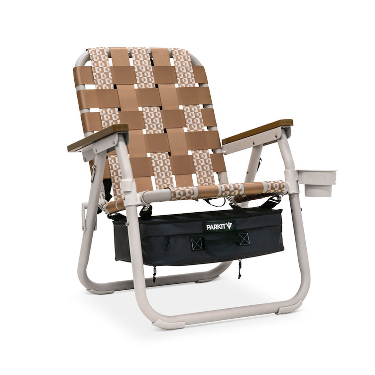 Beige and brown woven chair with a black storage bag on a white background