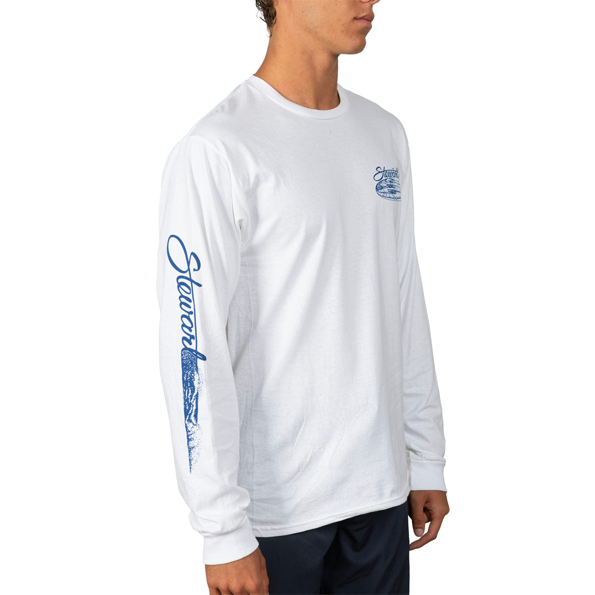 A man wearing a white long-sleeve t-shirt with blue graphics on the left chest and down the right sleeve, paired with dark pants, shown against a plain white background.