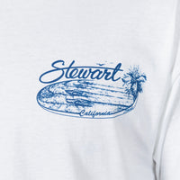 A close-up of a white t-shirt featuring a blue graphic print with the word 'Stewart' in cursive, a palm tree, a surfboard, and the word 'California' written along the bottom.