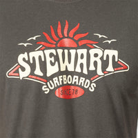 Close-up of a dark charcoal gray t-shirt featuring a vintage-style red and white graphic print that reads 'STEWART SURFBOARDS SINCE 78' with a sun and birds.