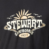 Close-up of a black T-shirt featuring a large vintage-style graphic with the words 'STEWART SURFBOARDS' and 'SINCE 78' in cream and beige tones, with a sun, waves, and birds above.