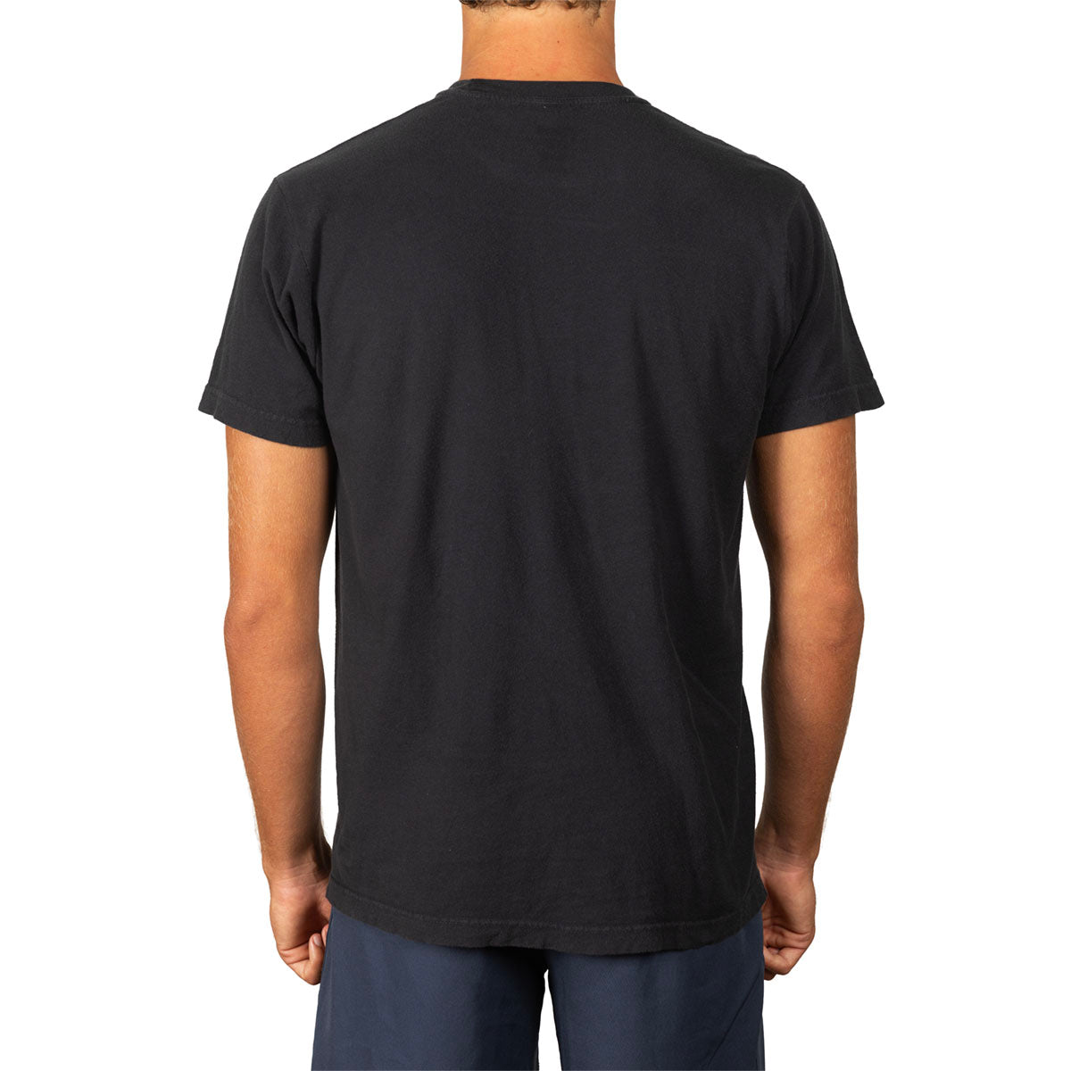 A man viewed from the back wearing a plain black short-sleeve crewneck t-shirt and navy blue pants, set against a solid white background.