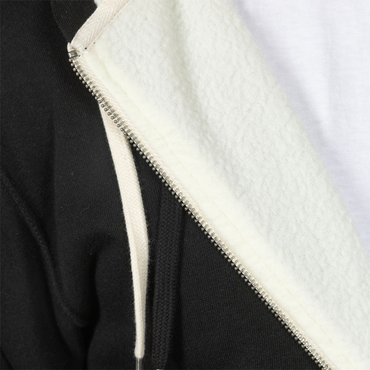 Close-up of a black zip-up hoodie with a thick white sherpa lining and a white drawstring, showing the silver zipper detail.