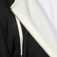 Close-up of a black zip-up hoodie with a thick white sherpa lining and a white drawstring, showing the silver zipper detail.