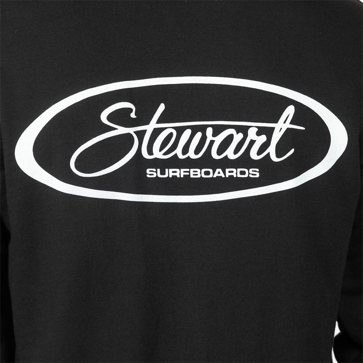 Close-up of a black long-sleeve shirt or sweatshirt with a large white oval graphic on the chest reading 'Stewart SURFBOARDS'.