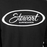Close-up of a black long-sleeve shirt or sweatshirt with a large white oval graphic on the chest reading 'Stewart SURFBOARDS'.