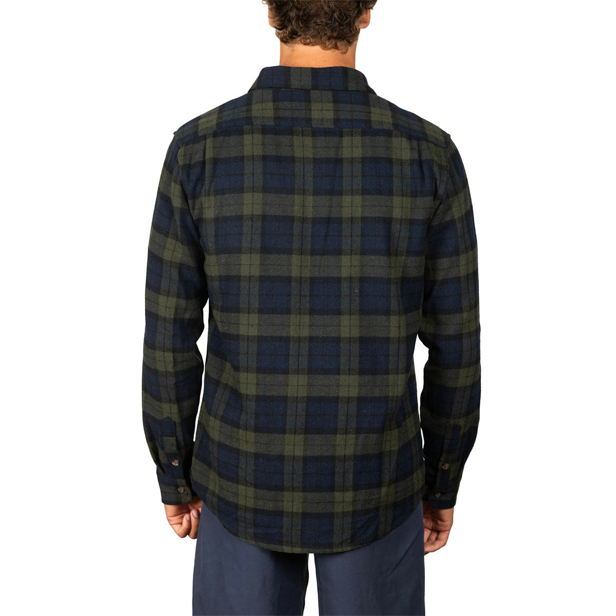 A man viewed from the back wearing a long-sleeve plaid button-up shirt in dark navy and olive green, paired with navy pants, against a plain white background.