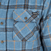 Close-up of a blue plaid button-up shirt with a chest pocket, brown buttons, and a small black brand patch reading 'Hemmant'.
