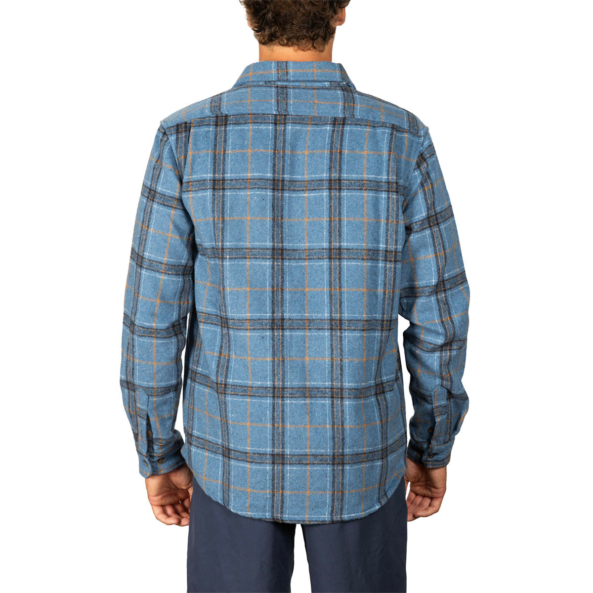 A man viewed from the back wearing a blue plaid flannel shirt with dark gray and orange lines, paired with navy pants, against a plain white background.
