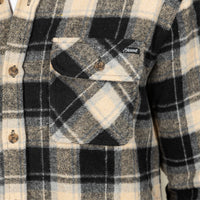 Close-up of a plaid flannel shirt with a chest pocket, featuring black, beige, and white check patterns and a small visible 'Savaget' brand tag.