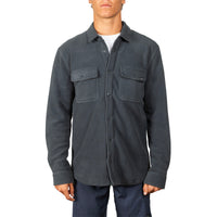 A man wearing a dark charcoal gray button-up shirt jacket with two chest flap pockets, photographed against a plain white background.
