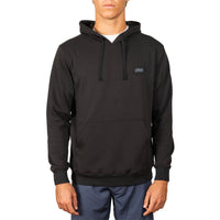 A man wearing a black pullover hoodie with a small rectangular chest logo patch, paired with blue pants, shown against a plain white background.