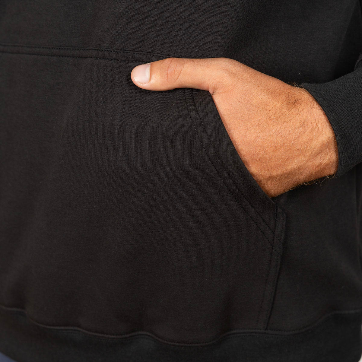 Close-up of a person wearing a black hoodie, with a hand tucked into the front kangaroo pocket.