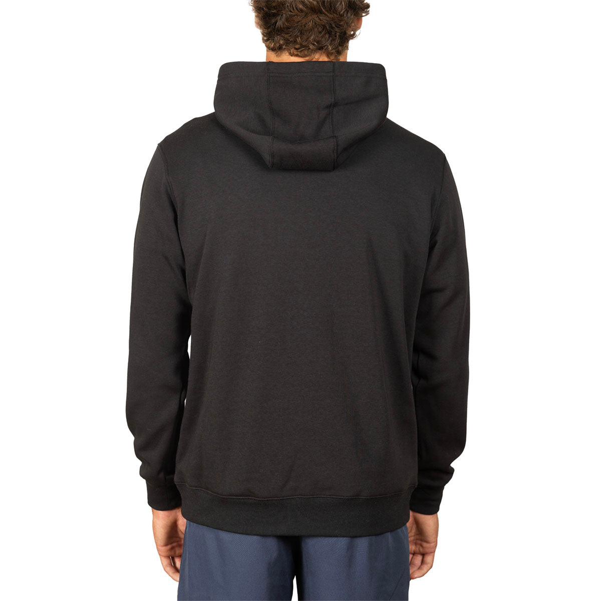 A man viewed from the back wearing a plain black pullover hoodie and blue pants against a clean white background.