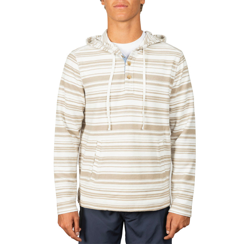 A man wearing a beige and white horizontally striped hooded long-sleeve shirt with a drawstring hood and a small button placket, paired with navy pants, against a plain white background.
