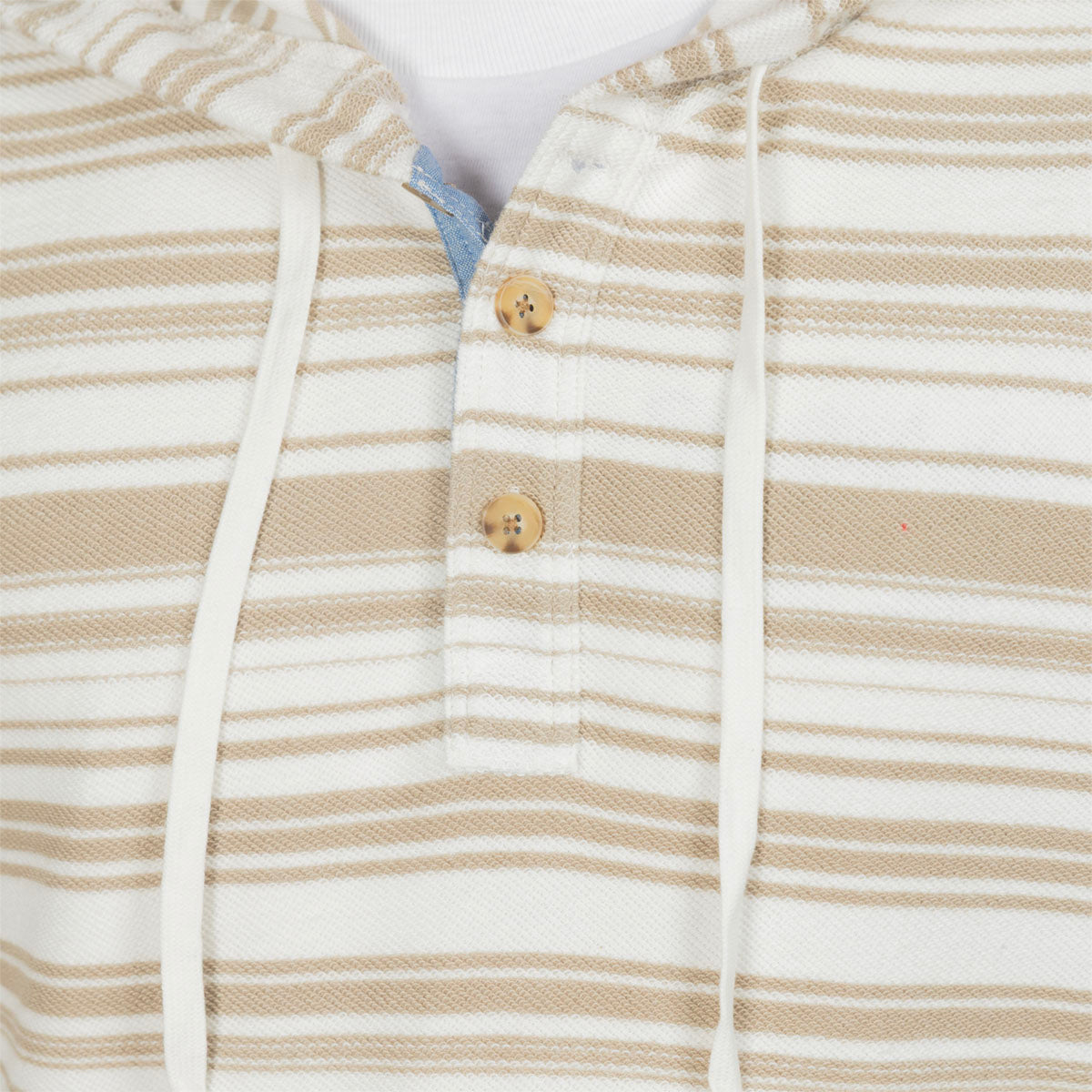 Close-up of a hooded knit top with beige and white horizontal stripes, featuring a buttoned placket with wooden buttons and white drawstrings.