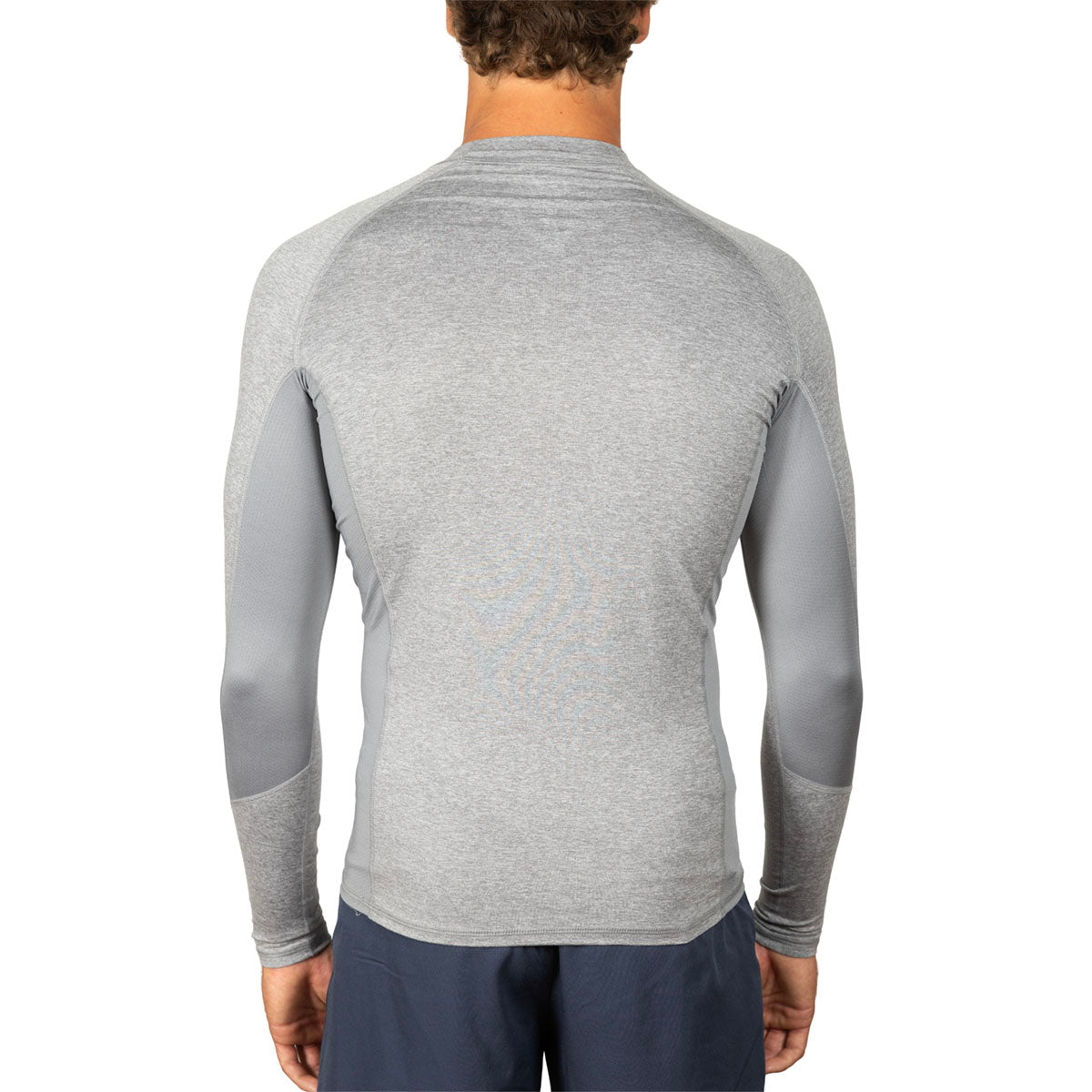 A man viewed from the back wearing a light gray long-sleeve athletic shirt with darker gray contrast panels on the sleeves, paired with navy pants, against a plain white background.