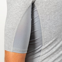 Close-up of a light gray athletic sleeve with a breathable mesh panel and a side slit showing the inner lining, worn by a model.