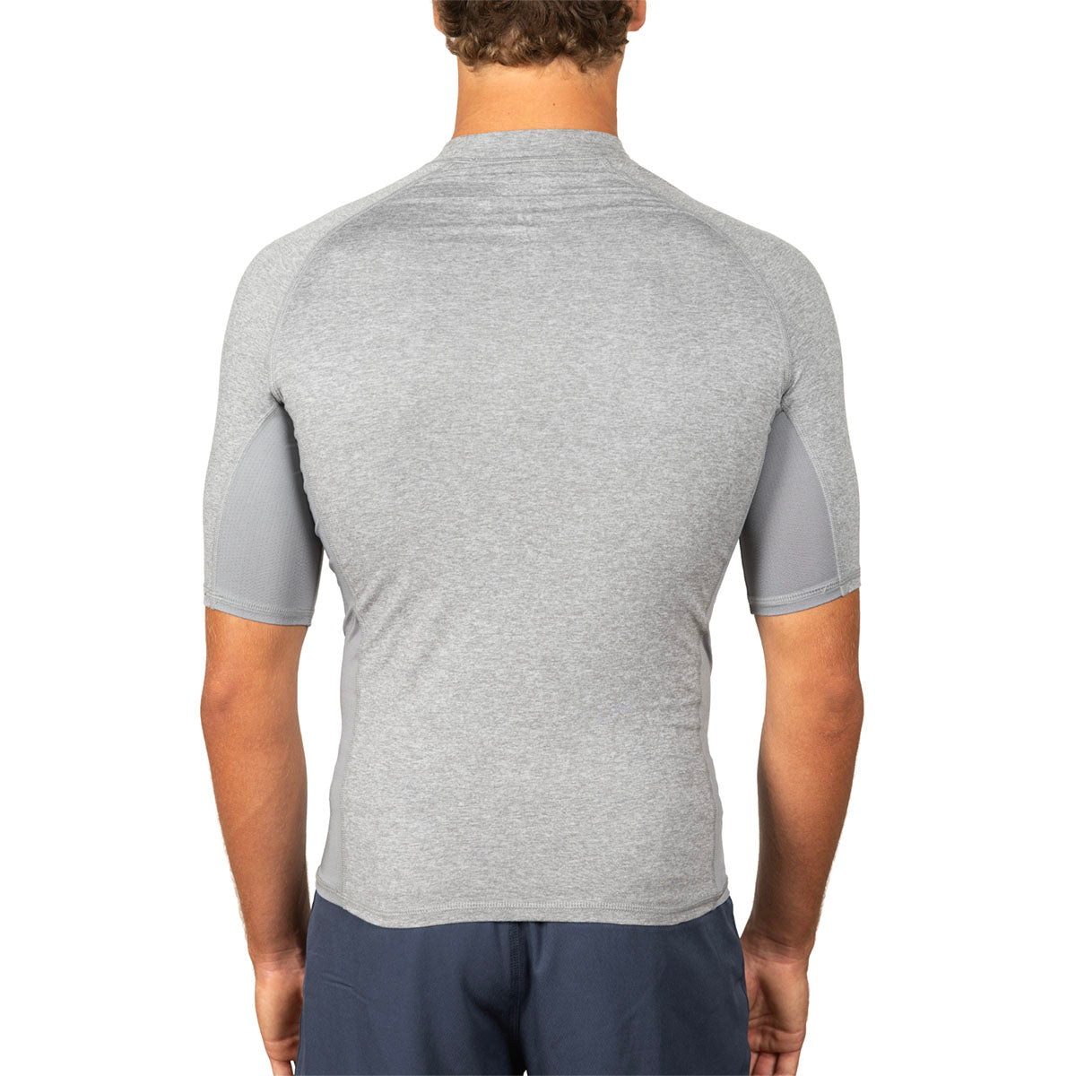 A man viewed from the back wearing a light gray short-sleeve athletic shirt with darker gray side panels, paired with navy shorts, against a plain white background.