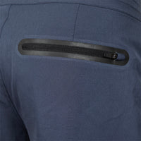 Close-up of a dark blue technical jacket showing a horizontal zippered pocket with a black zipper track and a small metal pull tab.