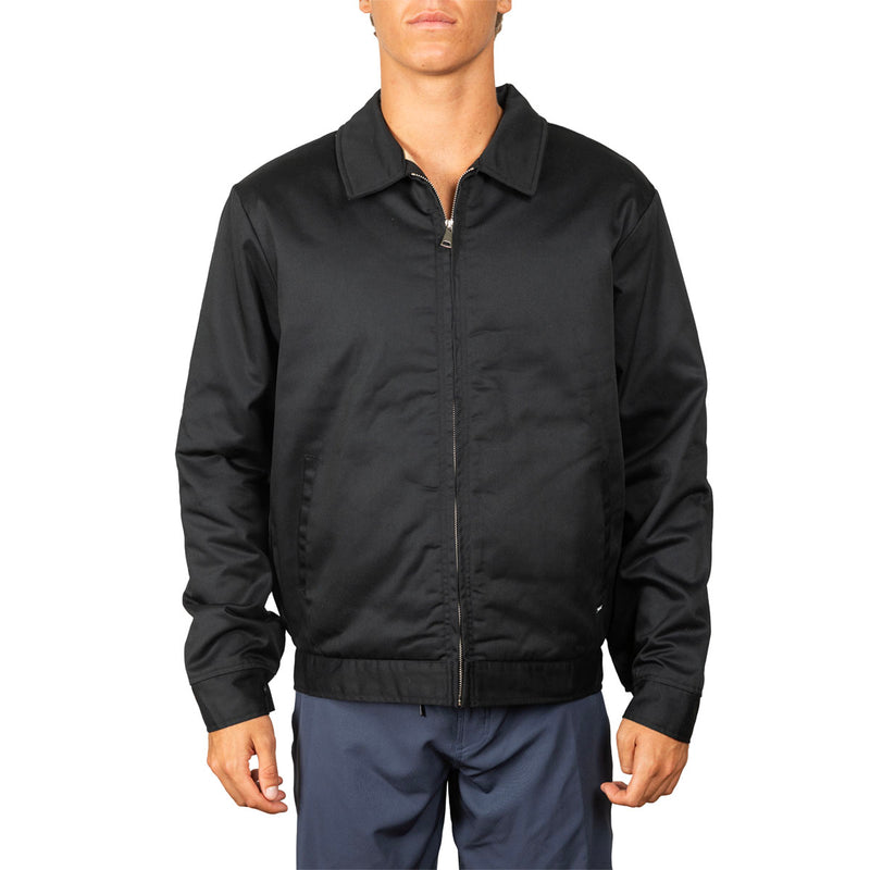 A man wearing a black zip-up jacket with a collar and ribbed hem, paired with navy pants, shown against a plain white background.