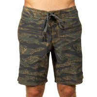 Men's board shorts with an all-over tiger stripe camouflage pattern in olive green, black, and tan, featuring a dark drawstring waist.