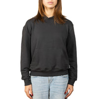 A woman wearing a black pullover hoodie with a front kangaroo pocket, paired with light-wash blue jeans, shown against a plain white background.