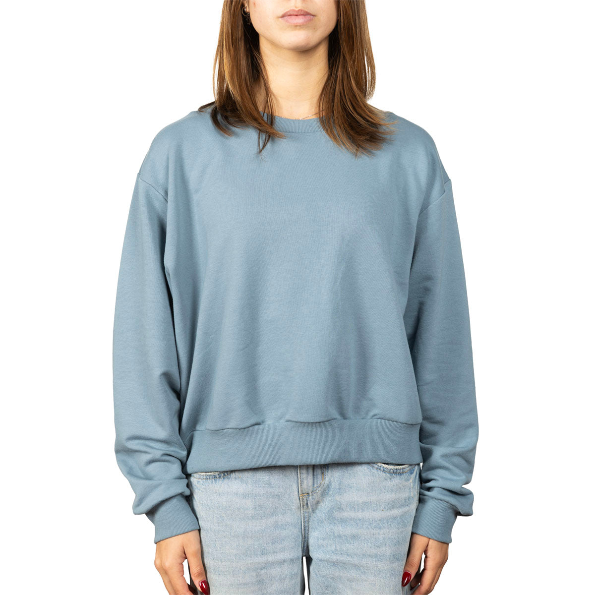 A woman wearing a dusty blue crewneck sweatshirt and light-wash jeans, shown from the neck down against a plain white background.