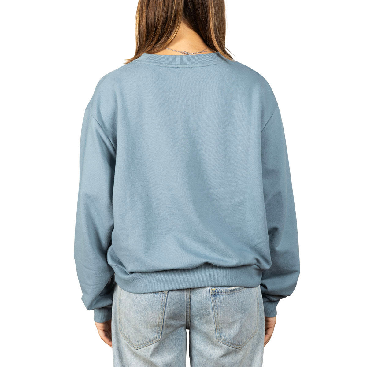 A person shown from the back wearing a dusty blue crewneck sweatshirt and light-wash jeans against a plain white background.