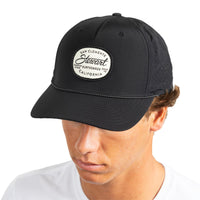 A man wearing a black baseball cap with a white oval patch that reads 'San Clemente Stewart Surfboards California.' The photo is cropped from the chest up against a plain white background.